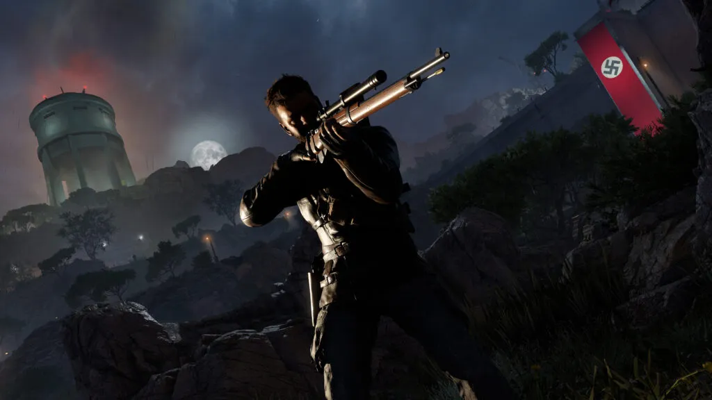 Harry Hawker from Sniper Elite: Resistance holds a rifle, standing on a rocky terrain with a full moon in the background and a tower displaying the Nazi flag nearby.