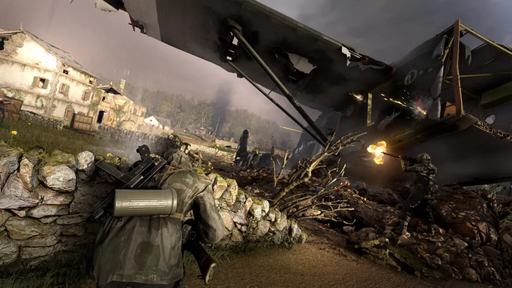 Two soldiers are engaged in combat. They are fighting by a downed aircraft. One hides behind a wall whilst the other has recently triggered his rifle.